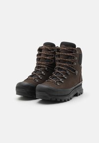 Bottes de randonnée en cuir marron avec des semelles en caoutchouc texturé, des crochets en métal pour les lacets, et des cols rembourrés pour le confort. Embouts renforcés inclus.