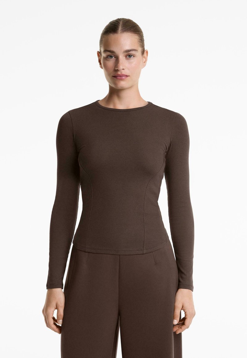 Barna hosszú ujjú felső bordázott anyagból. Testhez simuló fazon kerek nyakkivágással és finom varrási részletekkel. Simán tapintható textúra.