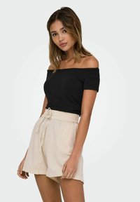 Sort off-shoulder t-shirt parret med lyse beige, løstsiddende shorts med bindebånd i taljen. Enkel, åndbar stof.