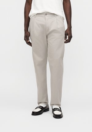 Light gray trousers made of smooth fabric, featuring a straight-leg cut, front pockets, and a button closure, paired with black and white loafers.