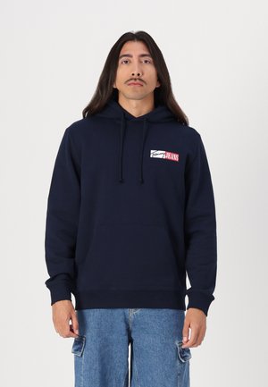 Mørkeblå hettegenser med en frontlomme, med en rød og hvit logo-patch. Laget av bomull, avslappet passform, ribbestrikkede mansjetter og hem.