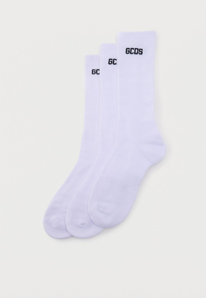 Trois paires de chaussettes blanches montantes empilées, chacune avec le logo noir "GCDS" près du bord supérieur.