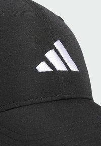 Czarna sportowa czapka wykonana z gładkiego materiału, z haftowanym białym logo z trzema skośnymi paskami. Wygięty daszek.