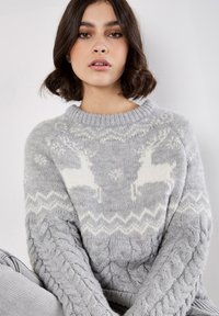 Grau gestrickter Pullover mit Rundhalsausschnitt, der weiße Rentierdesigns und ein Kabelstrickmuster an den Ärmeln und dem Saum aufweist.
