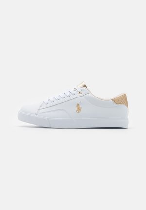 Sneaker bianche con una tomaia in materiale sintetico liscio, dettagli dorati sul tallone e sugli occhielli, e un logo dorato sul lato. Design a taglio basso.