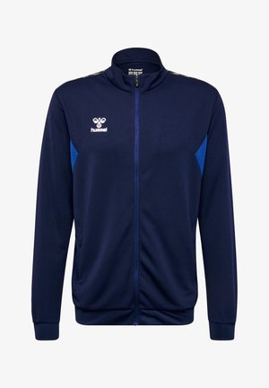 Dunkelblaues Sportjackett aus strukturiertem Gewebe, mit durchgehendem Reißverschluss, hohem Kragen und blauen Akzenten an den Seiten. Hummel-Logo auf der Brust.