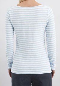 Vaaleansininen ja valkoinen raidallinen pitkähihainen paita, joka on valmistettu pehmeästä puuvillasta. Paitassa on pyöreä kaula-aukko ja istuva siluetti.