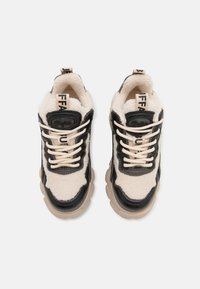 Baskets épaisses en cuir noir et tissu beige duveteux, lacets beige, semelles épaisses beiges, et languettes de tirage de marque sur fond blanc.