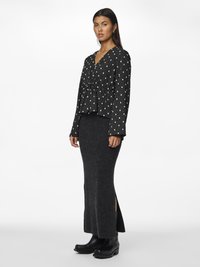 Mustvalge mustriga pika varrukaga topp koos kogutud talje ja tumehall ümara ribaga maksikleidiga, millel on külgrebendid, kantud mustade puhvritega.