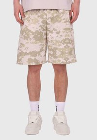 Beige Camouflage-Shorts mit lockerer Passform, aus leichtem Stoff gefertigt. Sie verfügen über ein weißes gesticktes Logo und subtile Texturvariationen.
