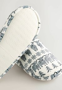 Pluizige witte slippers met een patroon van grijze beren en sneeuwvlokken. Zacht materiaal, ronde vorm en een textuurzool.
