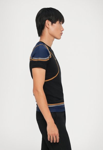 Camiseta negra con acentos azules en los hombros y un contorno dorado. Las mangas cortas y un diseño ajustado destacan el torso. Se lleva con pantalones oscuros.
