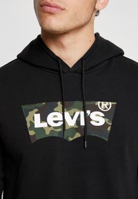 Felpa nera in cotone, con una grafica camouflage e il testo bianco "Levi's" sulla parte anteriore, completa di dettagli con cordini.