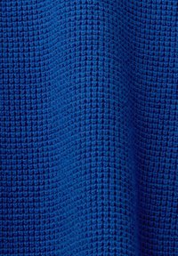 Gros plan sur un tissu bleu avec un motif de tissage gaufré texturé créant de petites indentations carrées et des crêtes surélevées.