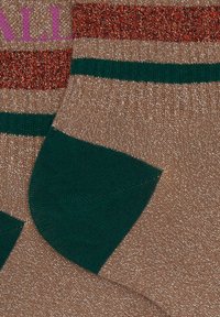 Un paio di calzini lucidi marroni con tallone verde e bordo a righe rosse, verdi e marroni, un calzino mostra una parte di testo rosa sul bordo.