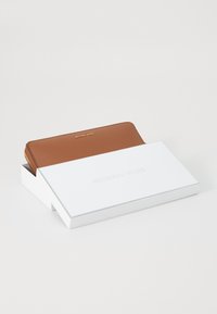 Brun lærwallet med strukturert overflate, gulllogo på forsiden og glidelåslukking, presentert i en hvit merkevareboks.