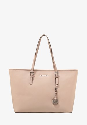 Beżowa torba typu tote marki Michael Kors z podwójnymi paskami na ramię oraz zawieszką z okrągłym logo MK w metalicznym wykończeniu.