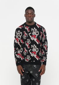 Zwart gebreid sweater met gedurfde graphic patroon met rode schedels en handen. Ronde halslijn, geribbelde manchetten en zoom, zachte textuur.
