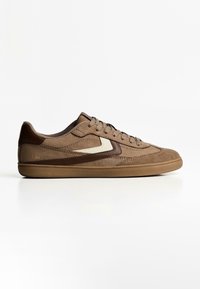 Brown suede sneakers with a rounded toe, textured accents, and a light cream design element on the side. Flat rubber sole.