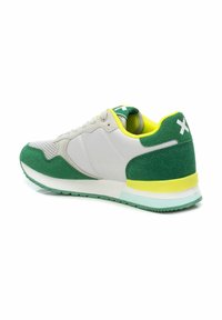 Zapatilla deportiva en verde y gris con parte superior de ante y malla, punta redondeada, suela ligera y detalles amarillos en el talón y la lengua.
