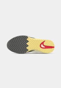 Sål med et zigzag-mønster; farverne inkluderer sort, gul og rød. Har en fremtrædende rød Nike swoosh-logo.