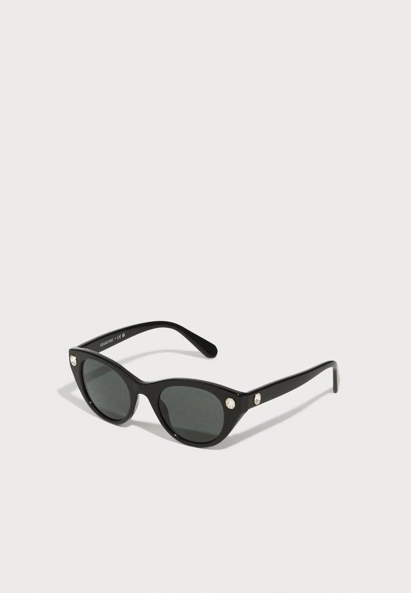Ochelari de soare negri, tip cat-eye, cu lentile întunecate, cadru din plastic lucios și două accente decorative în partea frontală, aproape de tâmple.
