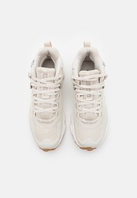 Baskets beige clair avec une tige en mesh texturé, un bout arrondi, des lacets plats et un col rembourré, dotées d'une semelle extérieure en caoutchouc beige.