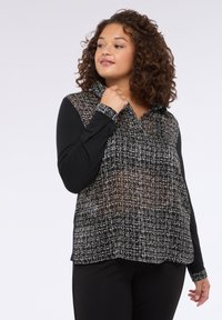 Czarny longsleeve z przezroczystą, w kratkę nakładką z białymi wzorami, kołnierzykiem oraz kontrastującymi, jednolitymi czarnymi rękawami.