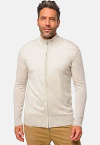 Un sweat à zip gris clair avec un col et des poignets côtelés, fabriqué en tissu doux. Présente une texture lisse et une coupe ajustée.