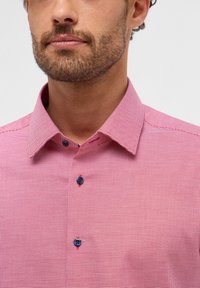 Rot kariertes Hemd mit einem subtilen texturierten Muster. Verfügt über einen klassischen Kragen und blaue Knöpfe. Kurzärmlig und aus leichtem Material.