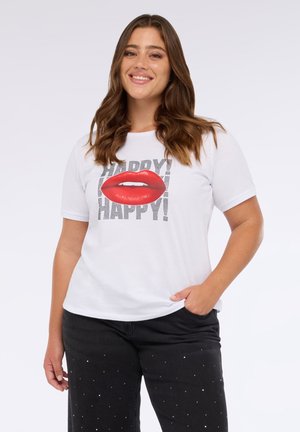 Weißes T-Shirt mit kurzen Ärmeln, das ein Grafikdesign von roten Lippen und dem Wort "HAPPY!" in schwarzem Text zeigt. Kombiniert mit schwarzen Hosen, die mit Nieten verziert sind.