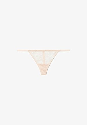 Lace thong panties in light peach, featuring thin straps and floral patterns. Soft texture with sheer sections and a seamless design.