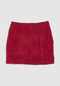 Roter Minirock mit strukturierten, floralen Rosettenmustern, die den Stoff bedecken, flach auf einem hellgrauen Hintergrund ausgestellt.