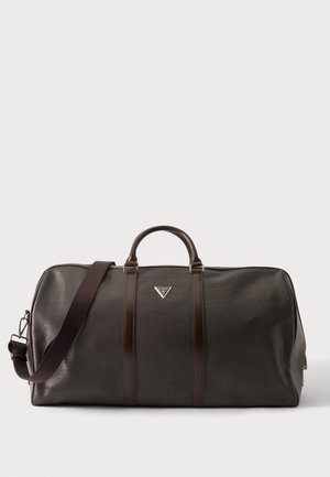 Tmavohnedá kožená taška typu duffel s dvojitými rukoväťami, nastaviteľným ramenným popruhom a malým trojuholníkovým logom značky na prednej strane v strede.