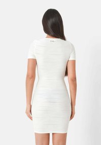 Abito bodycon bianco con maniche corte, strisce verticali testurizzate e orlo scallop. Progettato per una silhouette aderente.