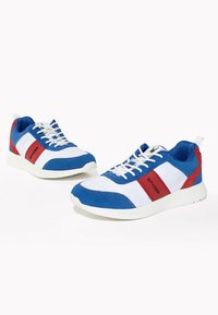 Blå och vita sportskor med röda accenter. Har en ovandel i mesh, texturerade överlägg och en vit gummisula. Snören och logodetaljer ingår.