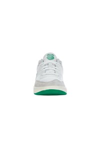 Fehér sneakers, hálós és samott anyagból, textúrázott zöld gumitalppal és zöld emblémával a nyelvén. Egyszerű fűzős design.