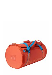Sac de sport rouge avec des bretelles et accents bleus, forme cylindrique, en tissu, avec une fenêtre d'identification transparente et un logo sur le côté.