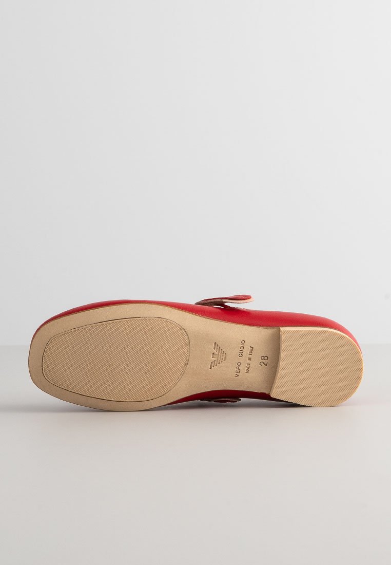 Scarpa in pelle rossa con tomaia liscia, forma arrotondata e suola in gomma con texture. Accentuata da una fascia e una stampa del logo.