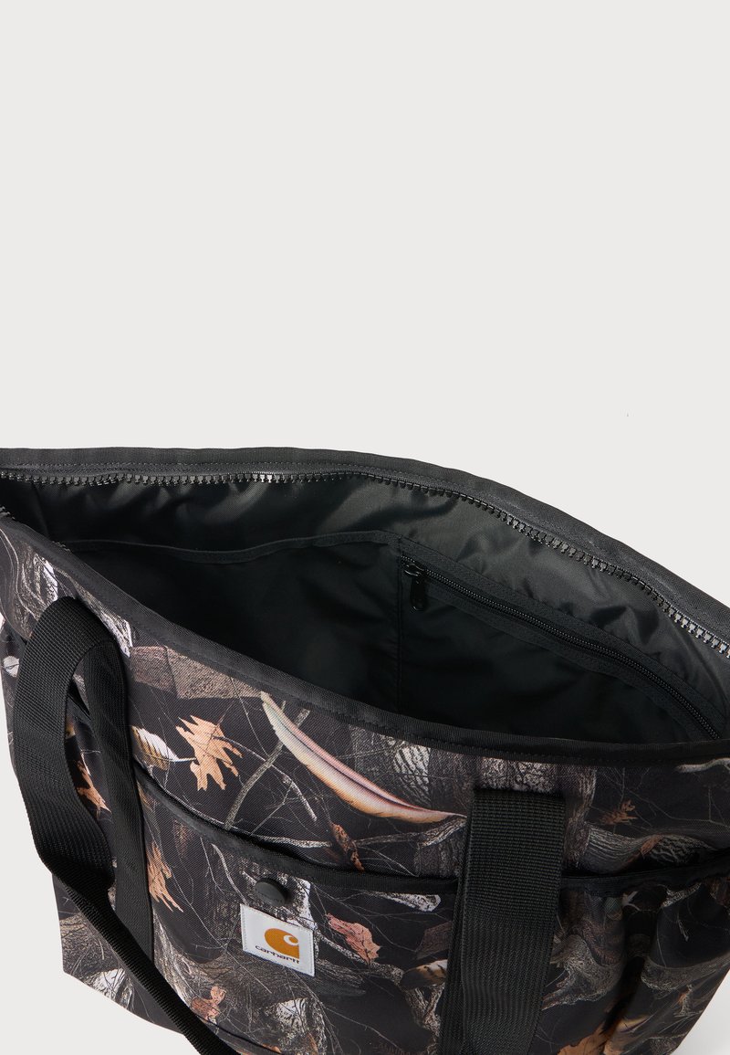 Black tote bag with brown leaf camouflage pattern, black handles, front pocket with button, and top zipper revealing black interior lining.