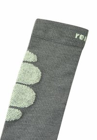 Calzino grigio con texture a coste, caratterizzato da un motivo a pois verde chiaro lungo un lato. Realizzato in materiale elastico per garantire comfort.