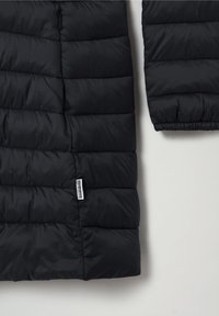 Zwarte gevoerde pufferjack sectie die de onderarm en de romp toont met horizontale stiksels en een klein wit Napapijri merklabel.