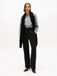 Light gray knitted cardigan with buttons, paired with high-waisted black trousers and pointed black heeled boots; black scarf accents.