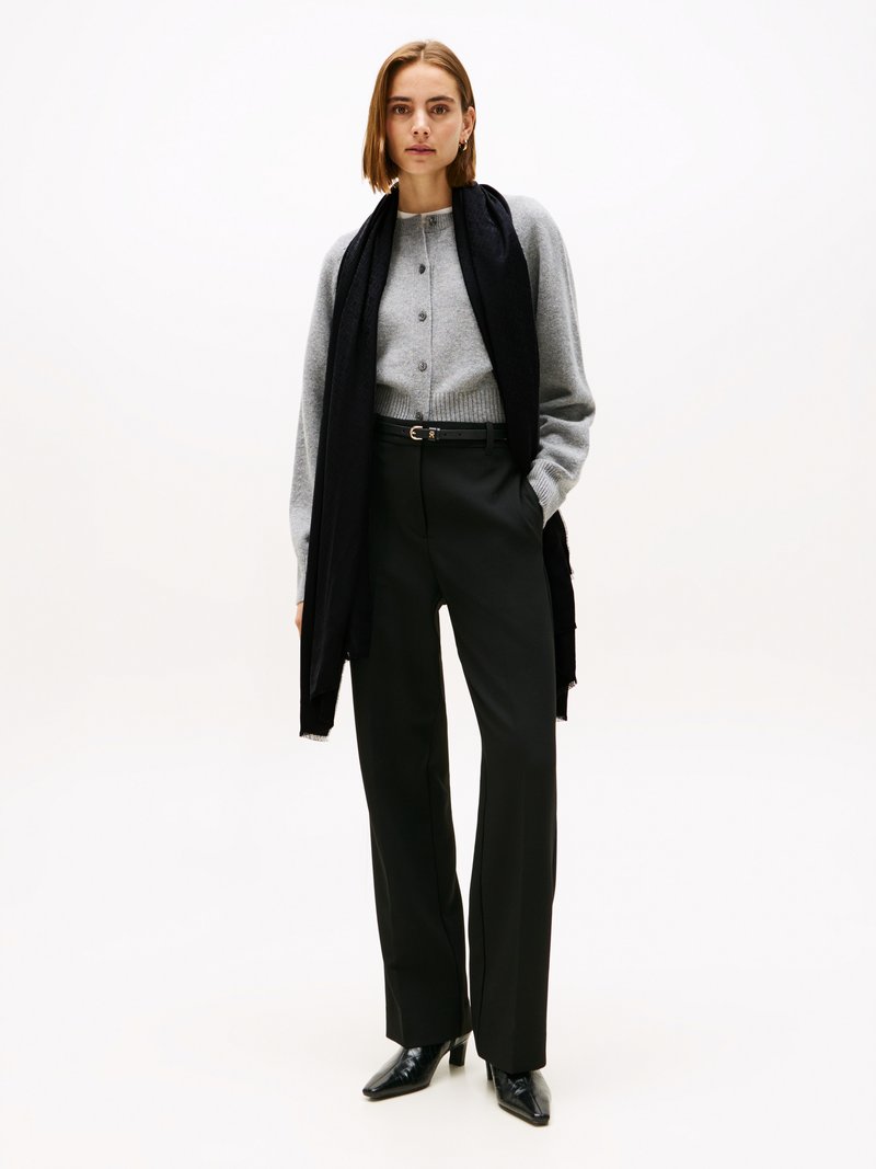 Light gray knitted cardigan with buttons, paired with high-waisted black trousers and pointed black heeled boots; black scarf accents.