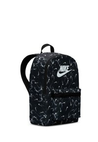 Mochila preta com um padrão em espiral de logótipos brancos da Nike. Apresenta um bolso frontal e alças de tecido. Textura suave e forma arredondada.