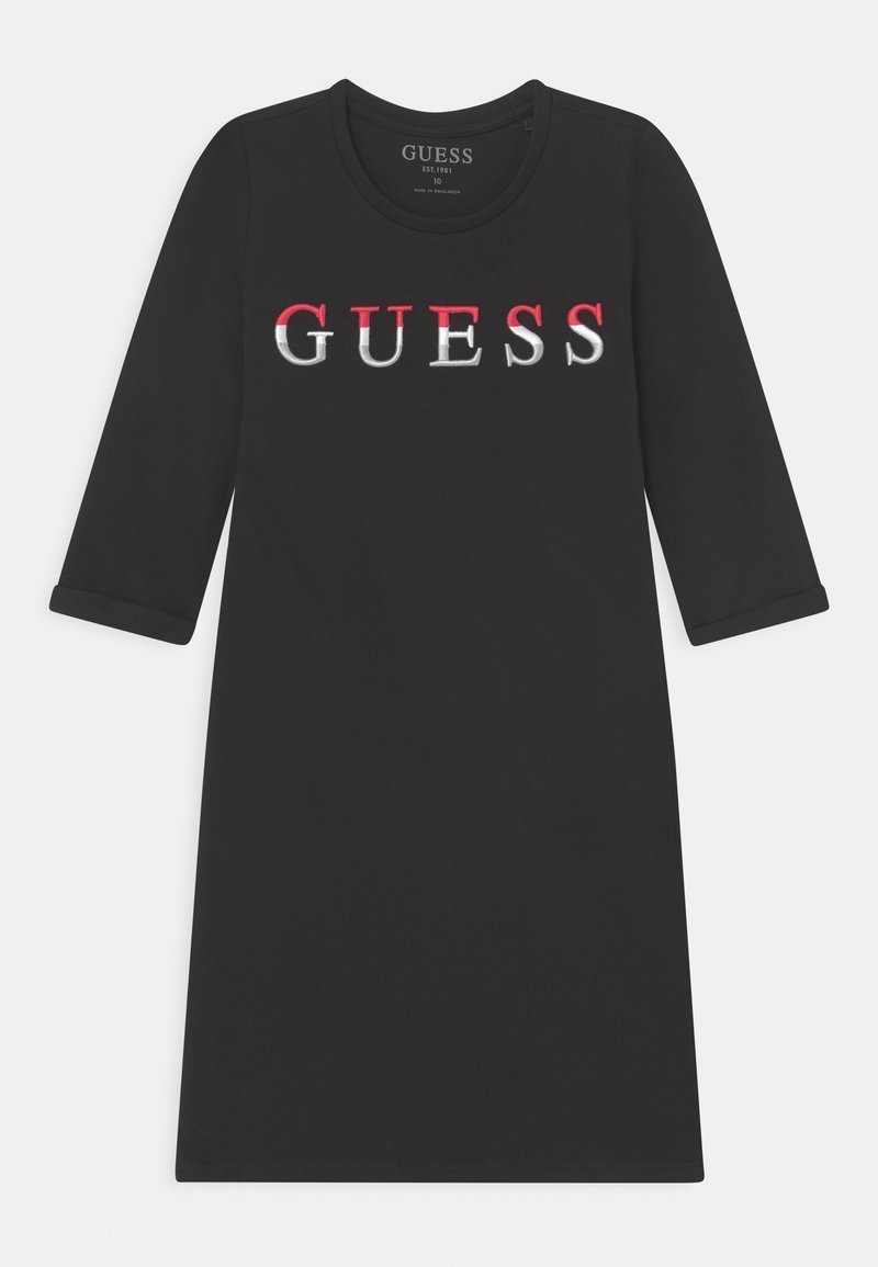Robe noire à manches trois quarts, col rond, mettant en avant un logo "GUESS" audacieux en rouge et blanc sur le devant. Texture de tissu douce.