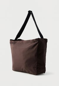 Smešnati smeđi torba od tkanine s glatkom teksturom, sa crnim podesivim remenom i bočnom džepom za dodatno spremanje.