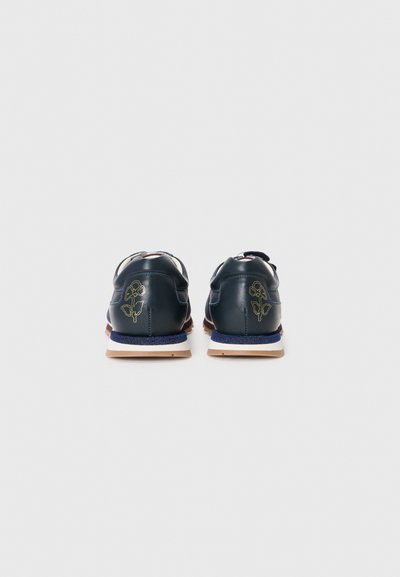 Navy leather sneakers with a textured finish, featuring gold floral embroidery, white laces, and a beige outsole.