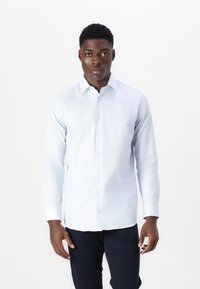 Light blue long-sleeve button-up shirt with a pointed collar, featuring a smooth texture and six front buttons, worn with dark pants.