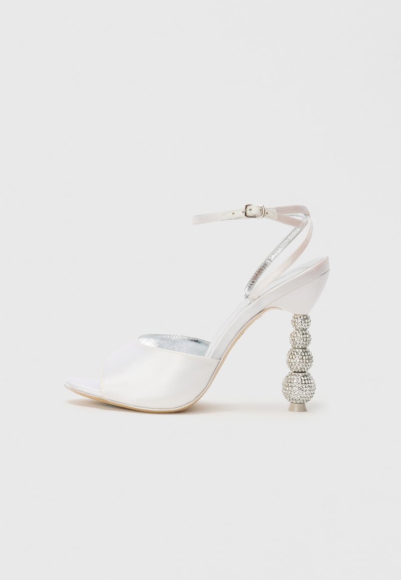 Sandalo con tacco alto aperto al davanti in satin bianco, con cinturino alla caviglia e un tacco decorativo scintillante con perline, caratterizzato da tre elementi rotondi.